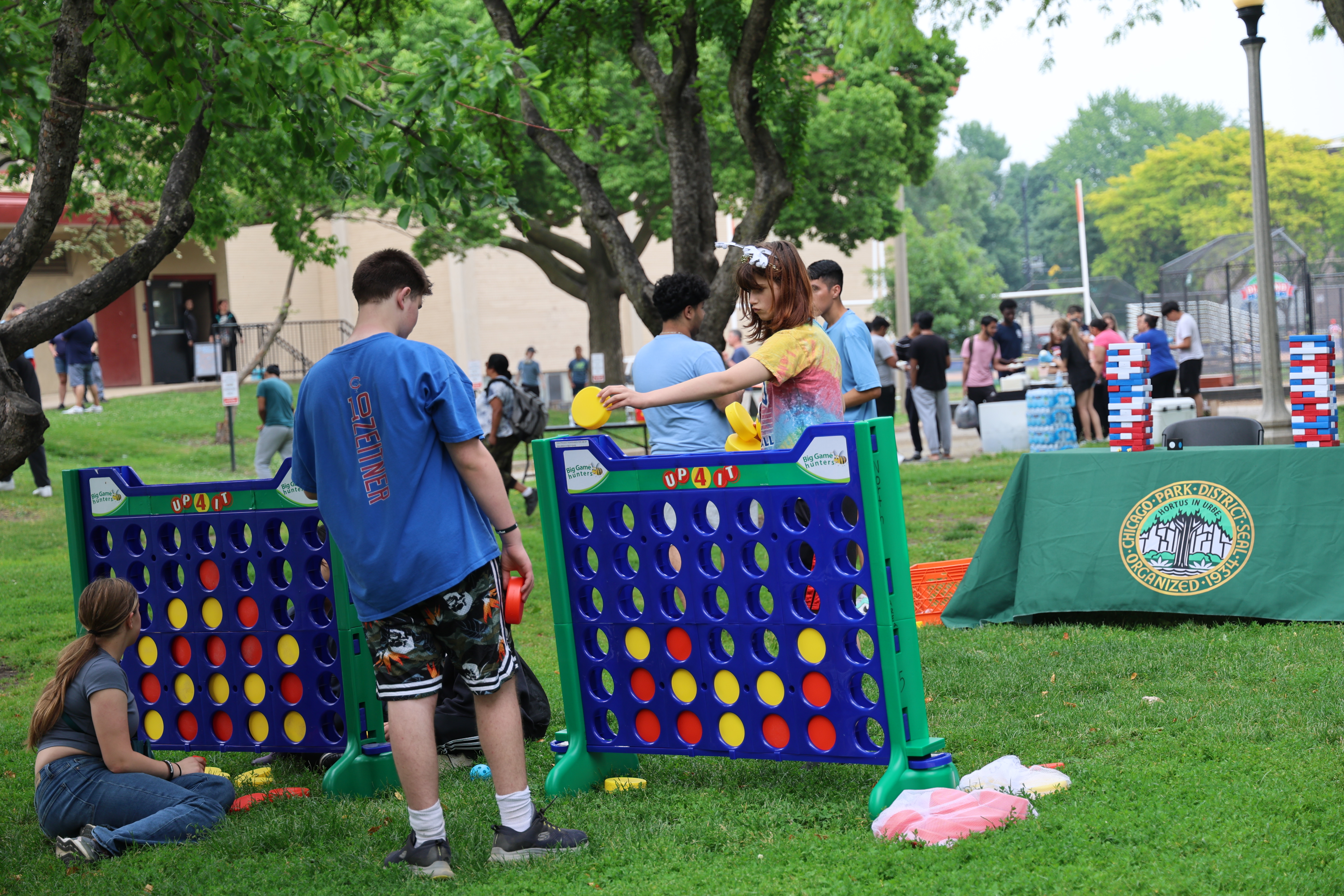 Teens play a giant Connect Four game in a park.